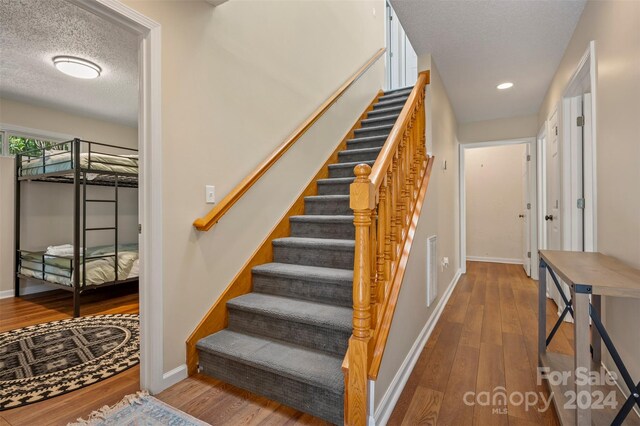 staircase featuring wood-type flooring and a textured ceiling