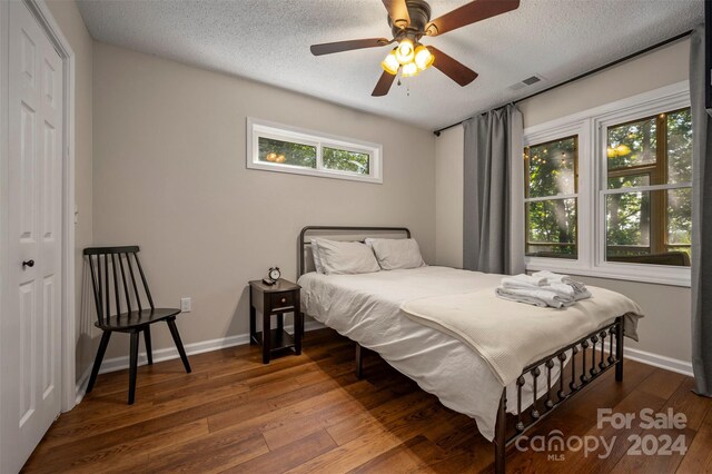 bedroom featuring a textured ceiling, ceiling fan, dark hardwood / wood-style floors, and a closet