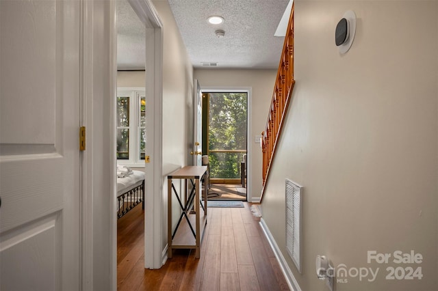 hall with a textured ceiling and wood-type flooring