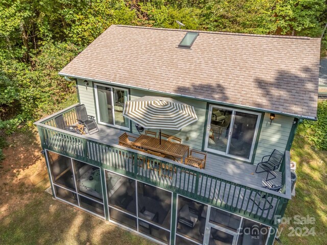 back of house with a wooden deck and a sunroom