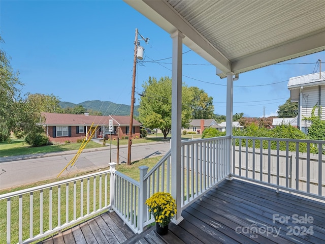 wooden terrace with a lawn and covered porch