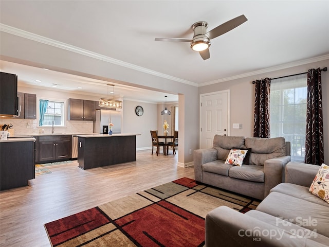 living room with ceiling fan, ornamental molding, sink, and light hardwood / wood-style flooring