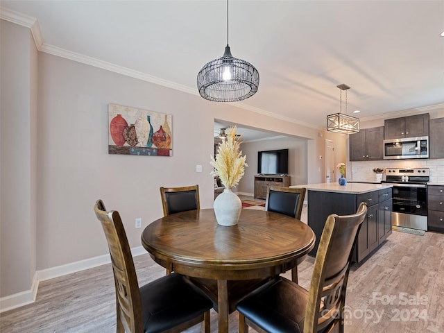 dining space with light wood-type flooring and ornamental molding