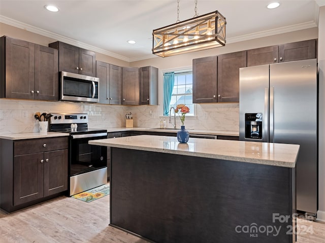 kitchen featuring hanging light fixtures, crown molding, light stone countertops, appliances with stainless steel finishes, and light hardwood / wood-style floors