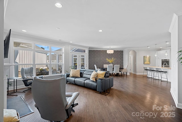 living room featuring sink, crown molding, and dark wood-type flooring