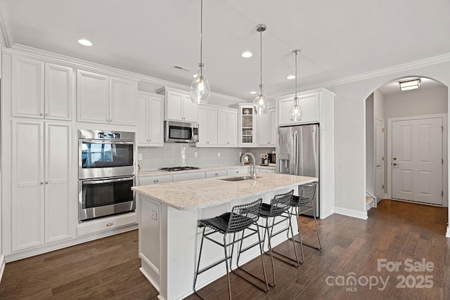 kitchen with appliances with stainless steel finishes, pendant lighting, white cabinetry, an island with sink, and sink