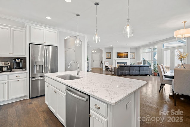 kitchen featuring sink, a kitchen island with sink, stainless steel appliances, white cabinets, and decorative light fixtures