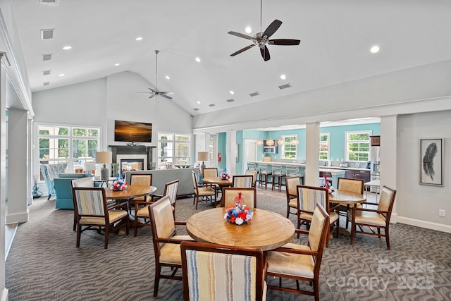 dining space with ceiling fan, a wealth of natural light, high vaulted ceiling, and dark colored carpet