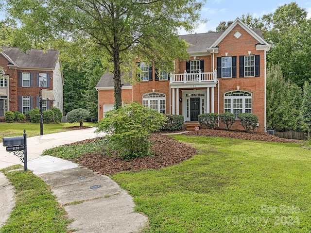 colonial-style house featuring a balcony and a front lawn