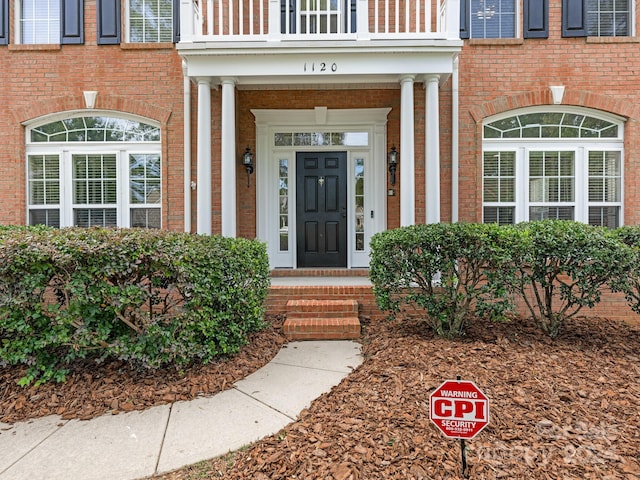 view of exterior entry with a balcony and covered porch