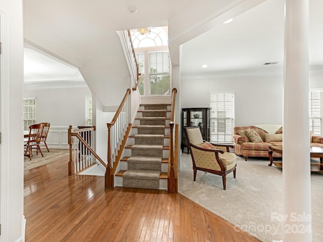 stairs featuring hardwood / wood-style floors and ornamental molding