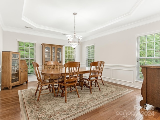 dining room featuring hardwood / wood-style flooring, crown molding, a raised ceiling, and a notable chandelier