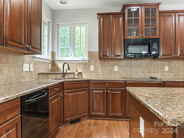 kitchen featuring black appliances, sink, light stone countertops, and light hardwood / wood-style floors