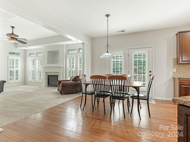 dining area with ceiling fan and light colored carpet