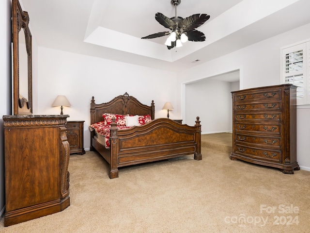 bedroom with a tray ceiling, ceiling fan, and light colored carpet