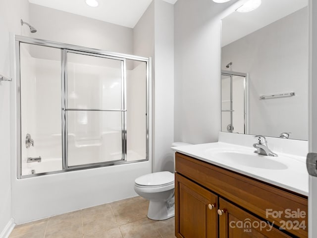 full bathroom featuring tile patterned flooring, toilet, bath / shower combo with glass door, and vanity