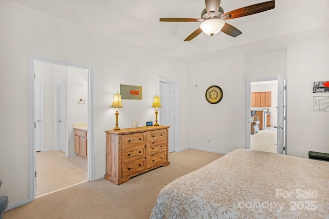 bedroom featuring a raised ceiling, connected bathroom, ceiling fan, and light colored carpet