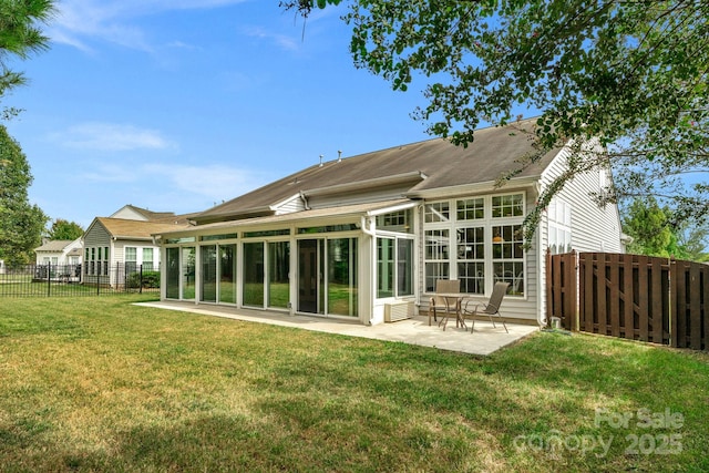 rear view of house featuring a lawn, a sunroom, and a patio