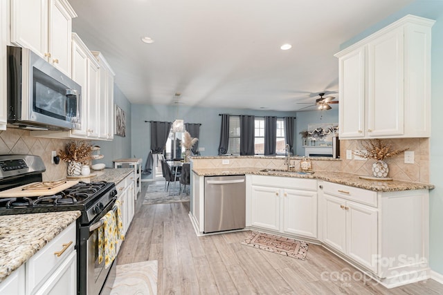 kitchen with kitchen peninsula, white cabinetry, sink, and appliances with stainless steel finishes