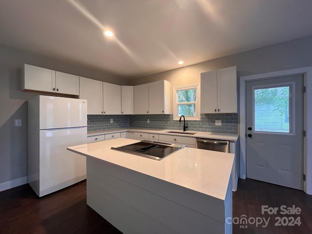 kitchen with white fridge, dark hardwood / wood-style flooring, a kitchen island, sink, and white cabinets