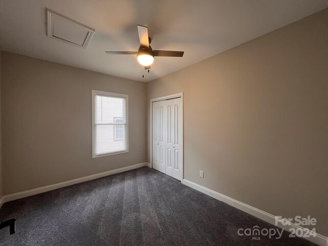 spare room featuring dark carpet and ceiling fan