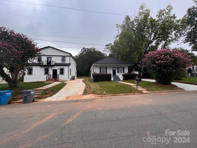 view of front facade featuring a balcony and a front yard