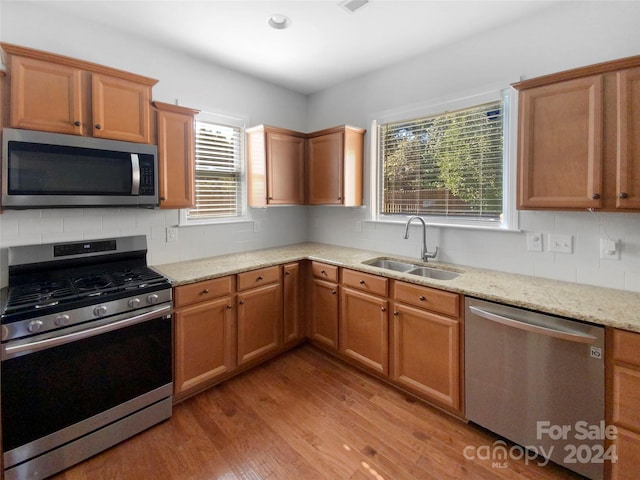 kitchen with a healthy amount of sunlight, stainless steel appliances, sink, and light hardwood / wood-style floors