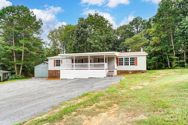 view of front of property with a garage, covered porch, a front yard, and an outbuilding