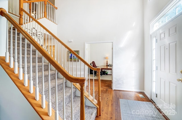 entrance foyer with hardwood / wood-style flooring and a towering ceiling