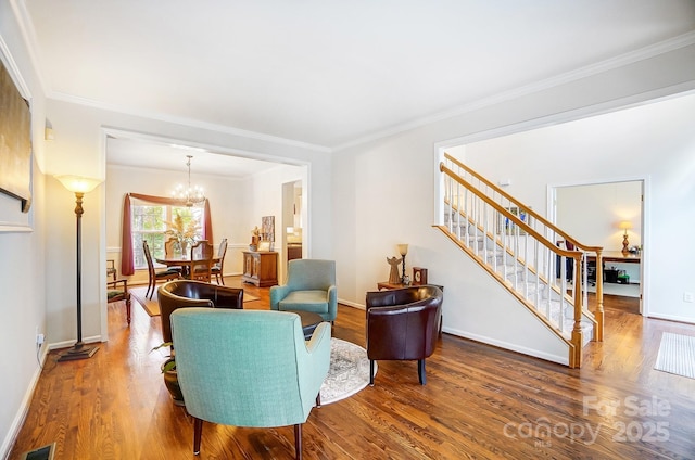 sitting room with ornamental molding, an inviting chandelier, and wood-type flooring