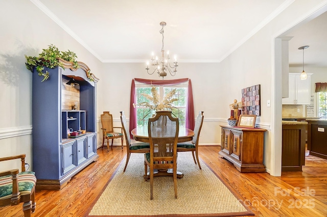 dining area with a notable chandelier, light hardwood / wood-style flooring, and crown molding