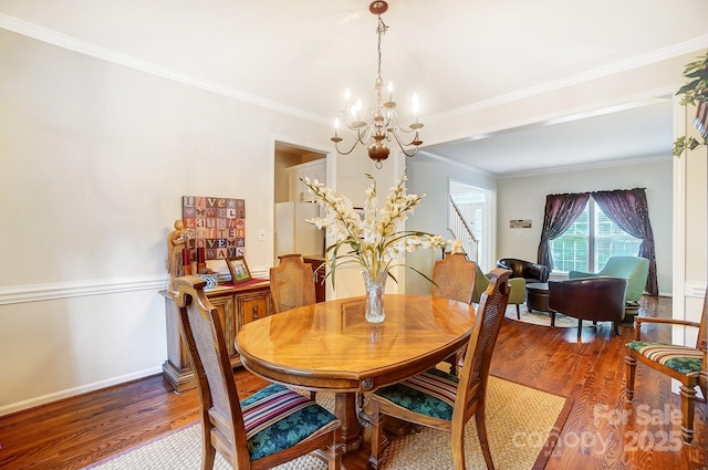 dining area with crown molding, a chandelier, and wood-type flooring