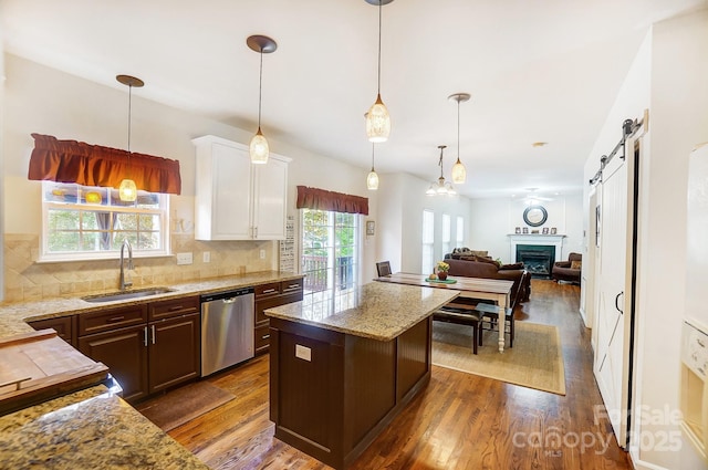 kitchen with a center island, dark brown cabinetry, sink, stainless steel dishwasher, and pendant lighting