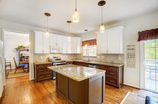 kitchen featuring decorative light fixtures, a kitchen island, hardwood / wood-style floors, appliances with stainless steel finishes, and white cabinets