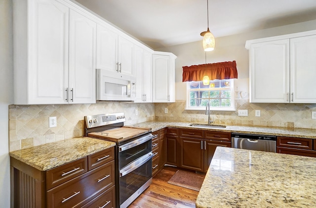 kitchen with sink, stainless steel appliances, pendant lighting, and white cabinets