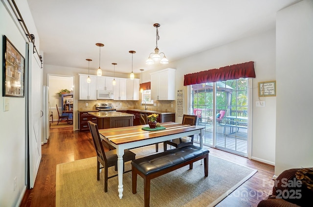 dining space with a barn door, sink, and dark wood-type flooring