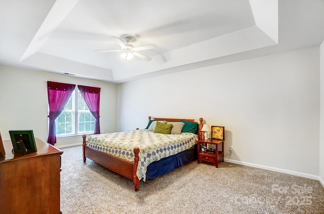 carpeted bedroom featuring ceiling fan and a tray ceiling