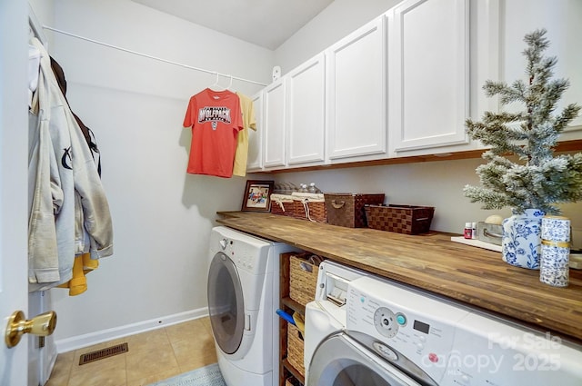 clothes washing area featuring light tile patterned flooring, cabinets, and washer and dryer