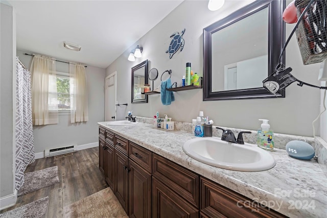 bathroom featuring wood-type flooring, baseboard heating, and vanity