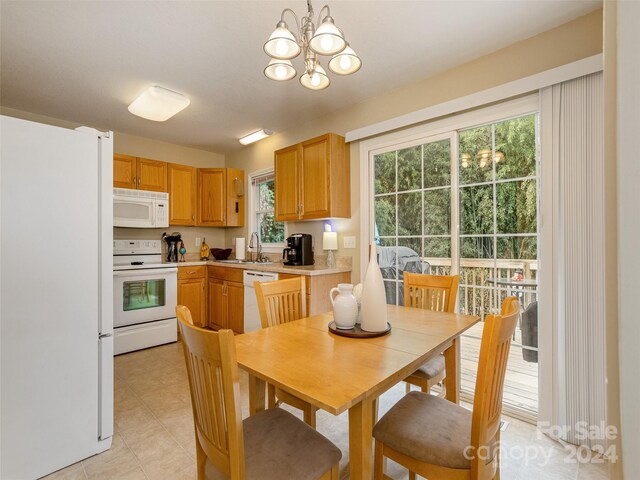 kitchen with white appliances, a wealth of natural light, a chandelier, and sink