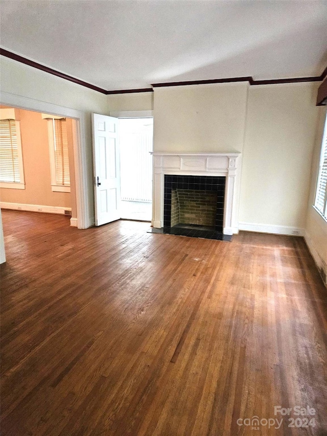 unfurnished living room featuring wood-type flooring, a tile fireplace, crown molding, and a textured ceiling