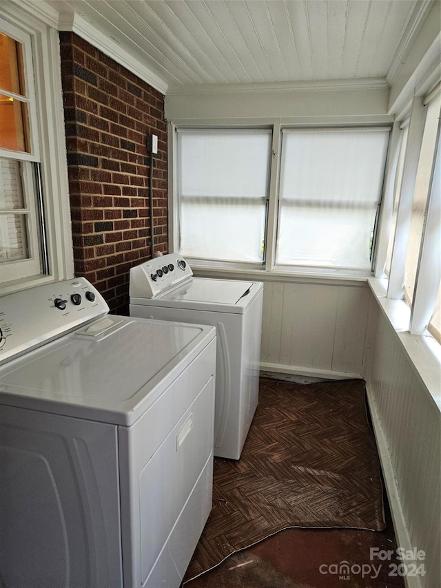 laundry area with ornamental molding, brick wall, dark parquet floors, and washing machine and dryer