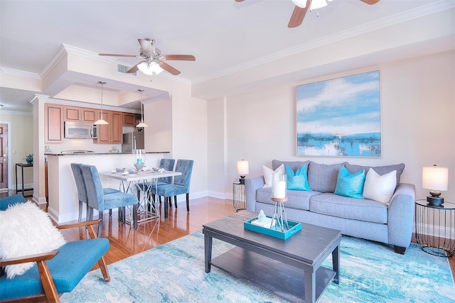 living area with a ceiling fan, baseboards, visible vents, light wood finished floors, and crown molding