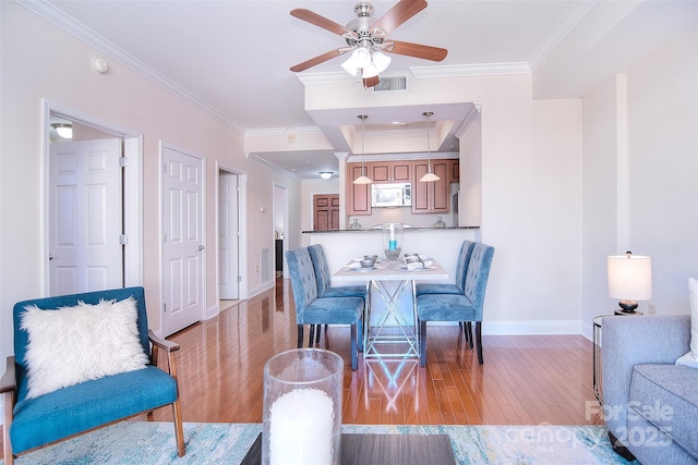 dining room featuring baseboards, crown molding, visible vents, and light wood-style floors