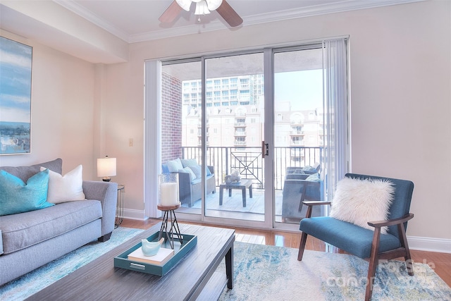 living area with baseboards, ornamental molding, ceiling fan, and wood finished floors