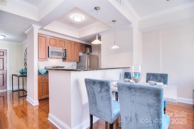 kitchen with light wood-type flooring, brown cabinetry, pendant lighting, and stainless steel appliances