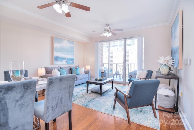 living area featuring ornamental molding, light wood-type flooring, a ceiling fan, and baseboards