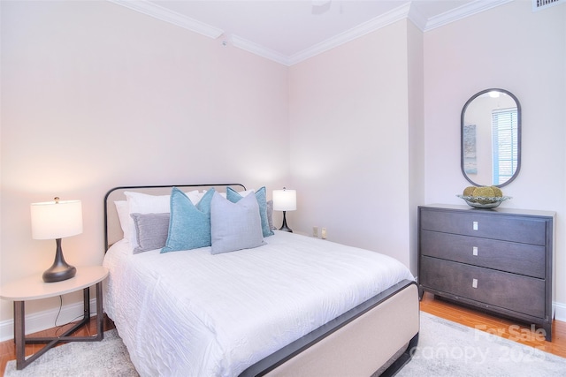 bedroom featuring light wood-type flooring, visible vents, ornamental molding, and baseboards