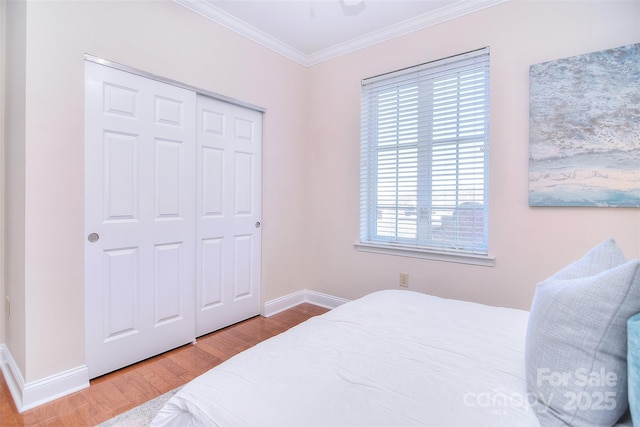 bedroom featuring ornamental molding, a closet, baseboards, and wood finished floors