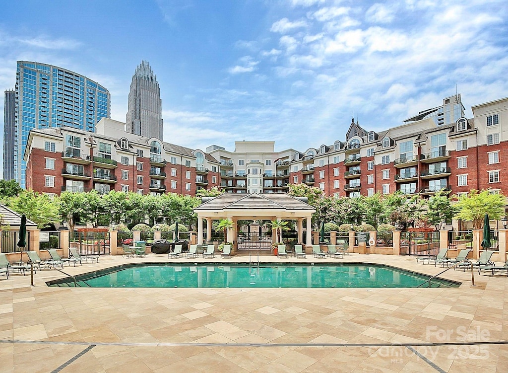 pool with a gazebo, a patio area, fence, and a city view